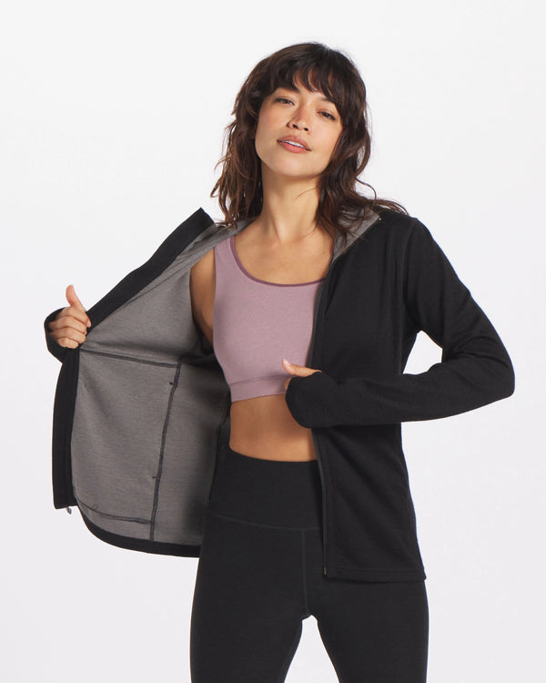 A woman wearing a Black Women's Full zip. She is also wearing an alpaca bra underneath.