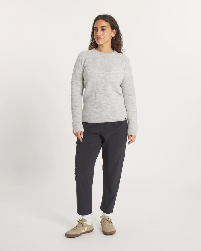 Woman wearing the Women's Mountain Crew Sweater in Light Grey  and black pants on a white background