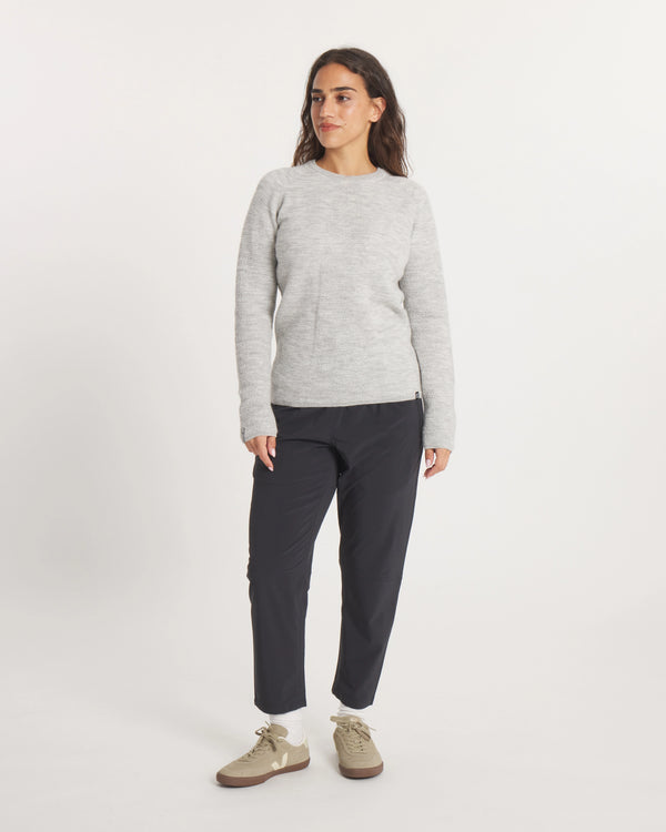 Woman wearing the Women's Mountain Crew Sweater in Light Grey  and black pants on a white background
