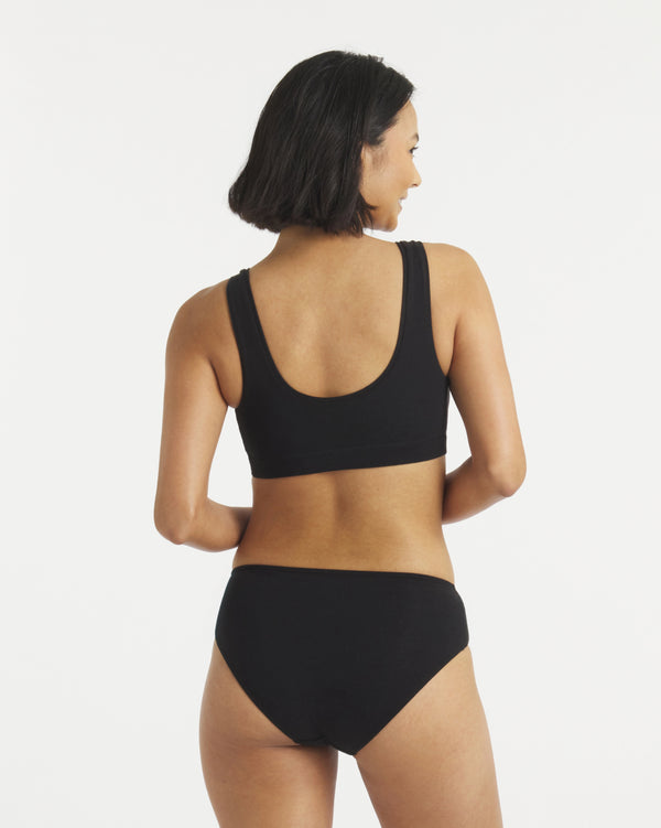 Back view of Women’s Essential Scoop Bralette in black showcasing wide straps, scoop back neckline and supportive underband on light gray background