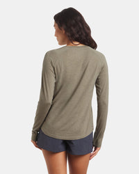 Back view of Women’s Sol Crew long-sleeve sun shirt in elm showing slim fit, raglan sleeves, and curved hem on model against a light background