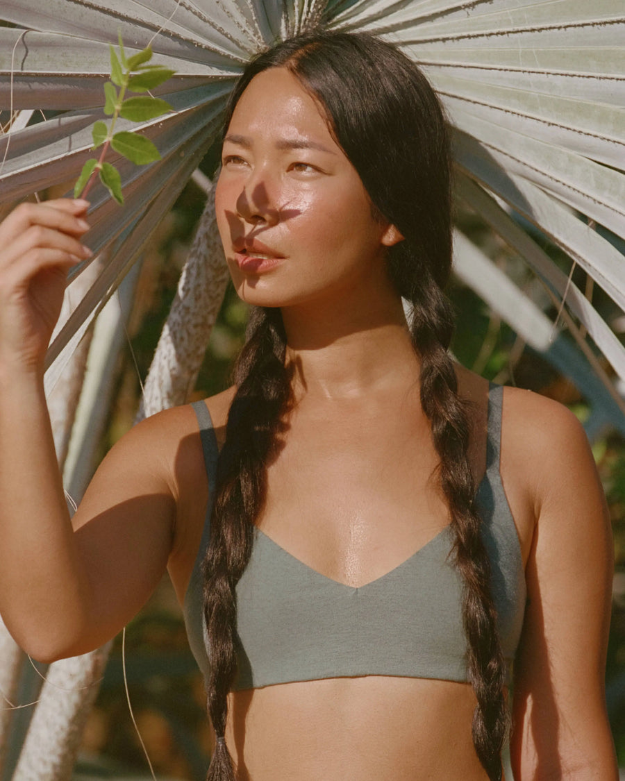 Front view of Women’s Essential Triangle Bralette in balsam green on model, deep V cups, wireless padless, Inca-pattern straps