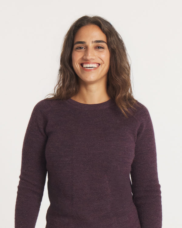 Woman wearing the Women's Mountain Crew sweater in Eggplant against a plain background