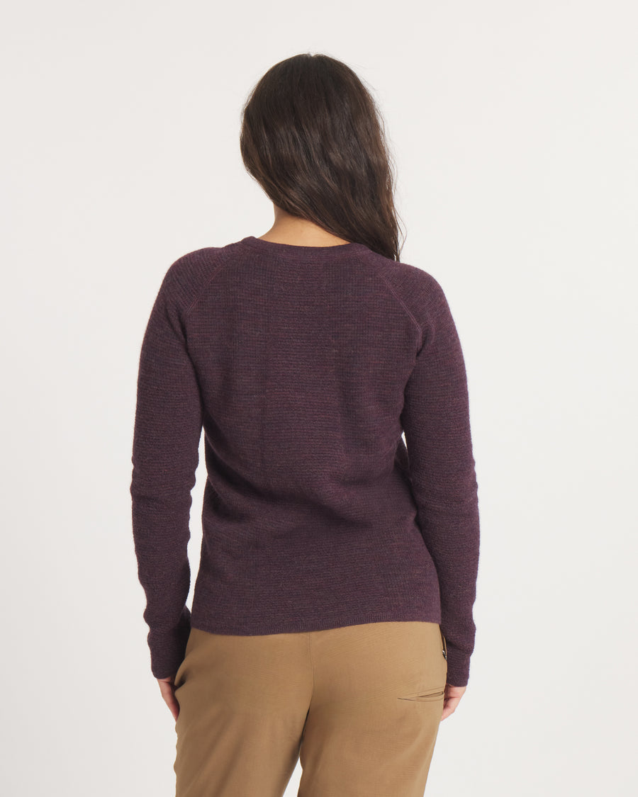 Person wearing the Women's Mountain Crew sweater in Eggplant and brown pants on a white background