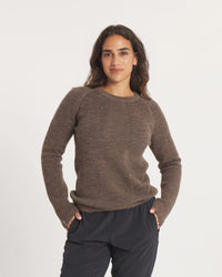 Woman wearing a Women's Mountain Crew sweater in Wood and dark pants on a white background