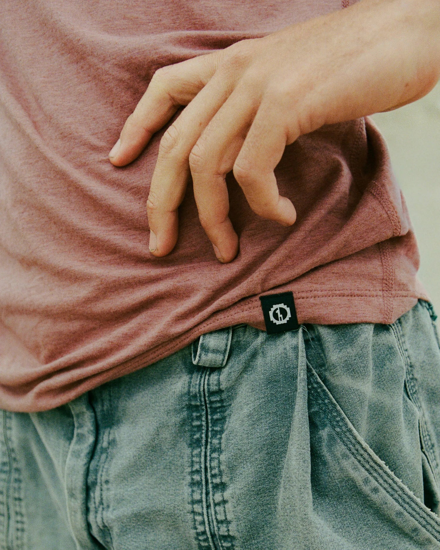 Person wearing a pink shirt and green pants with a blurred background