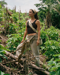 Front of Women’s Essential Tank in black on model, cropped fit with wide straps and shelf bra against green background