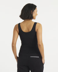 Rear view of Women’s Essential Tank in black showing cropped fit, wide straps, and built-in shelf bra on gray background