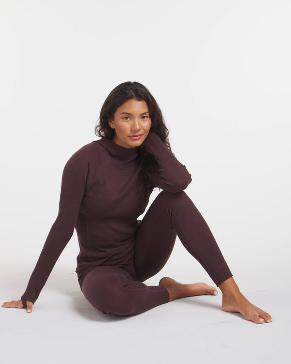 Woman Sitting on Floor Wearing Uva / Dark Purple Alpaca Wool Thermal Pants for Skiing and Outdoors – PAKA Apparel