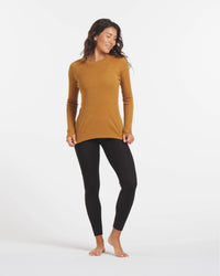 Full Height Shot of Woman Stretching Waist of Golden Brown Alpaca Wool Thermal Baselayer Shirt for Skiing – PAKA Apparel