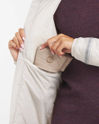 Hand Placing Tan Beanie in Side Pocket of Noni / White Women's Apu Lightweight Puffer Jacket – PAKA Apparel
