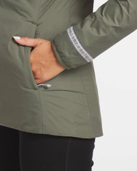 Close-Up of Left Hand in Pocket of Thyme / Dark Green Women's Apu Lightweight Puffer Jacket – PAKA Apparel