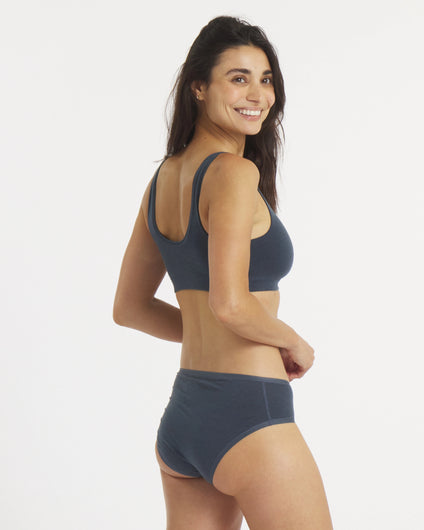 Woman wearing the Navy Mid Rise Brief and Scoop bralette set on a white background