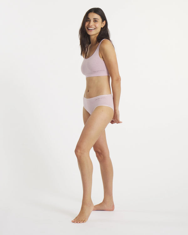 Woman wearing a light pink bikini set on a white background