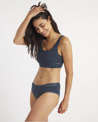 Woman wearing a navy blue sports bra and underwear set on a white background