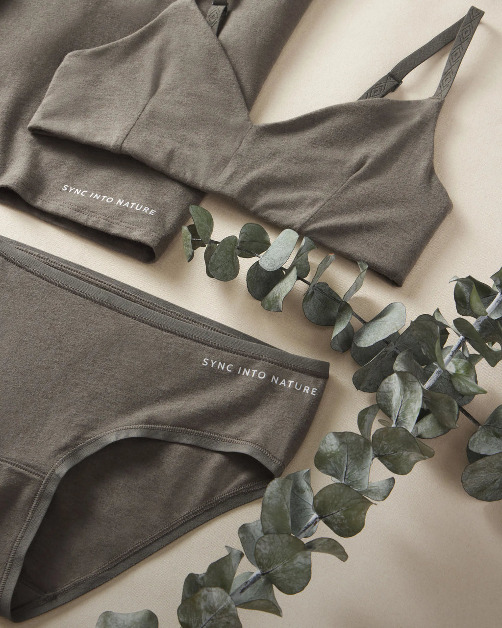Women's Forage Triangle Bralette and Mid-Rise Brief with 'SYNC INTO NATURE' branding on a light background with eucalyptus leaves.