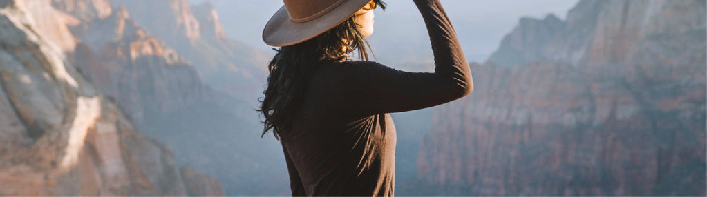 Woman Wearing Brown Long Sleeve Hiking Shirt with Mountains in Background  – PAKA Apparel