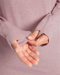 Close-up of Women’s Sol Hoodie sleeve showing hidden thumbhole and lightweight knit in woodrose on model