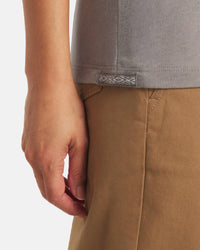 Close-up of Women’s Essential V-Neck in Stone showing side hem and woven Inca ID tag on model wearing tan pants
