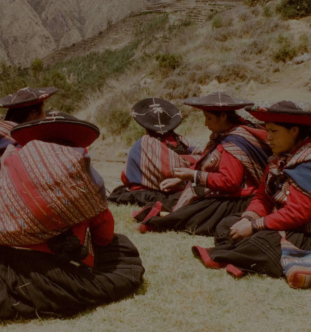 Peruvian women weaving colorful textiles outdoors in traditional clothing