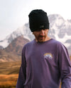 A man wearing our purple Explore Peru long sleeve in front of Ausangate mountain