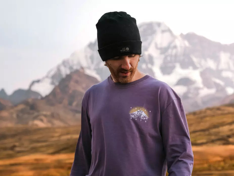 A man wearing our purple alpaca long sleeve next to Ausangate mountain in Cusco, Peru