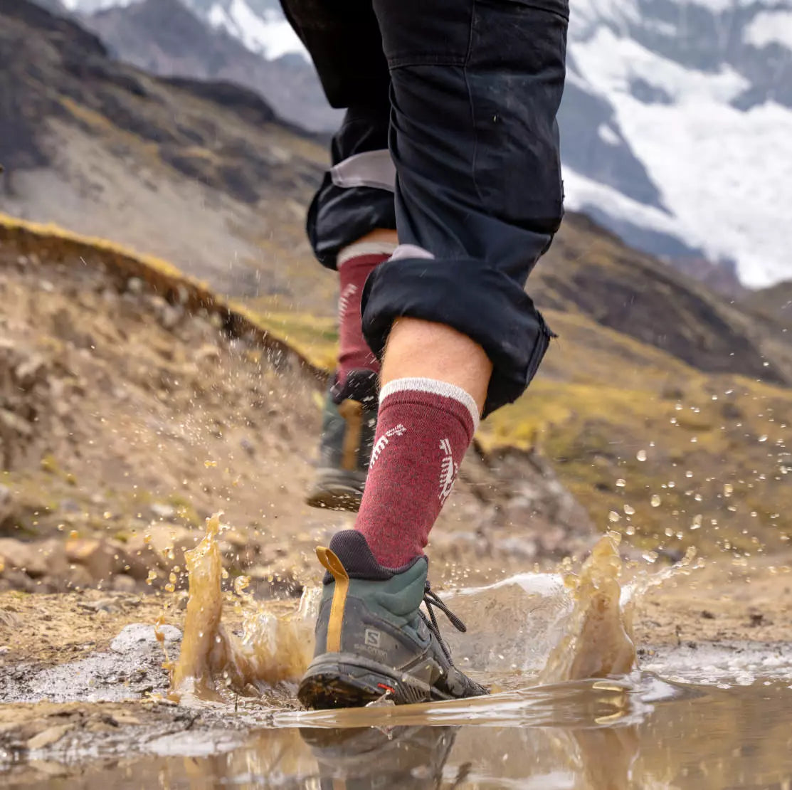 A hiker wearing our costa socks walking over a puddle of water