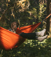 Soft alpaca socks worn by an outdoors person in an orange hammock with a brown dog