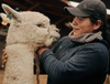 A women and a white alpaca looking at each other 
