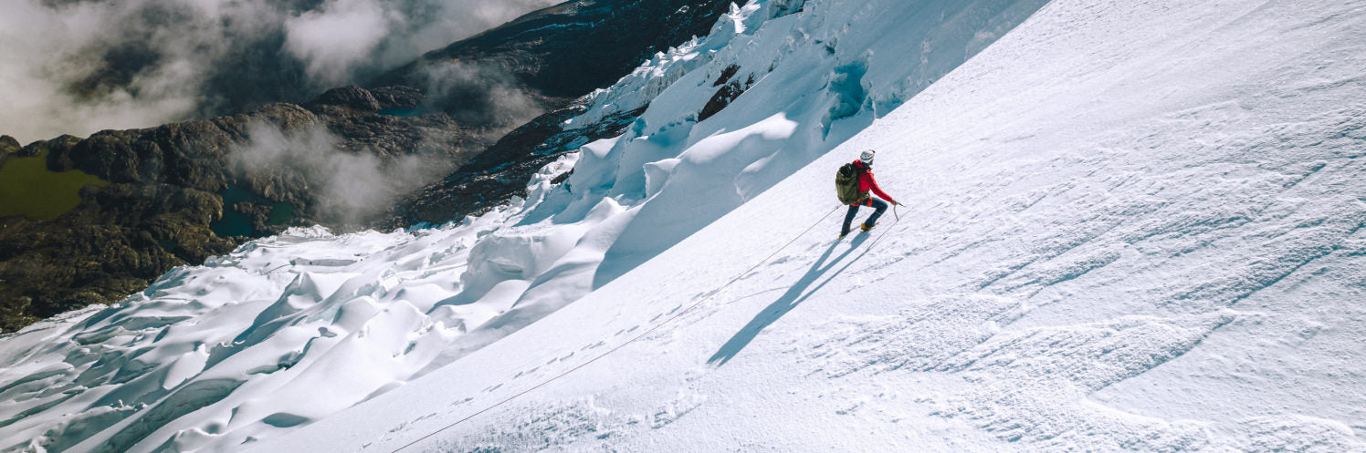 A man climbing a snowy mountain waring our red Pakafill Puffer jacket