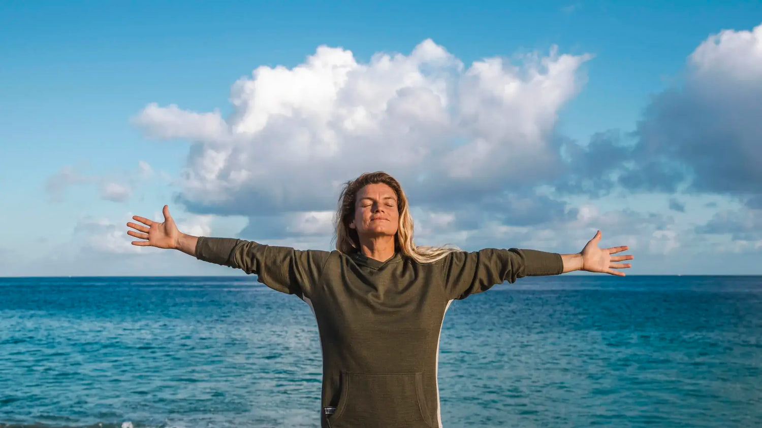 Woman with outstretched arms in front of ocean 