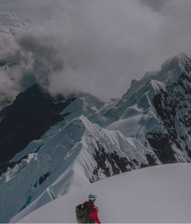 Climber on Peak of Snowy Mountain in Red Apu Puffer Jacket – PAKA Apparel