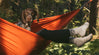 Soft alpaca socks worn by an outdoors person in an orange hammock with a brown dog