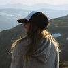 A girl smiling and wearing an alpaca Hoodie with some mountains in the background