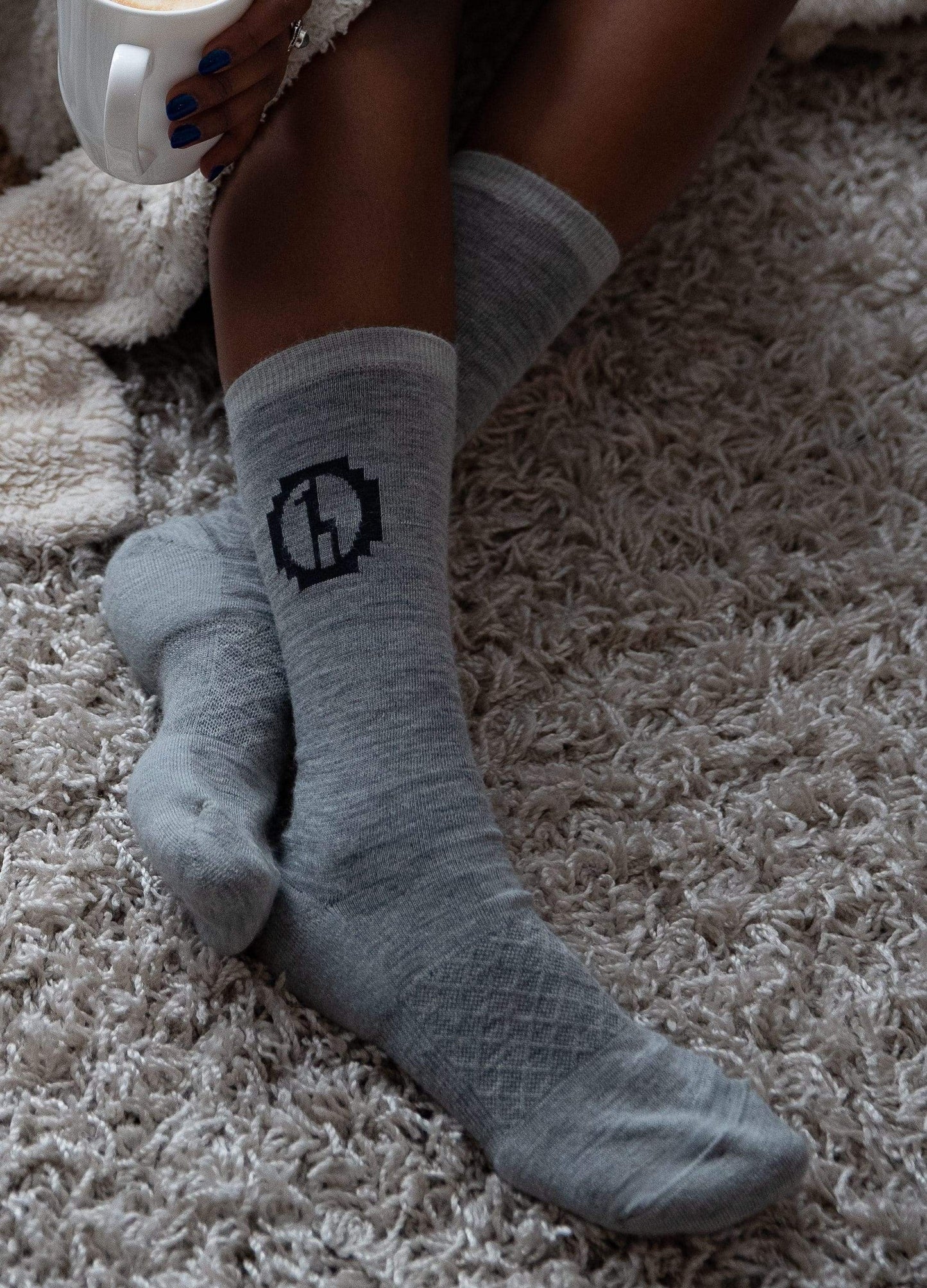 Baby alpaca socks on rug with model legs and coffee