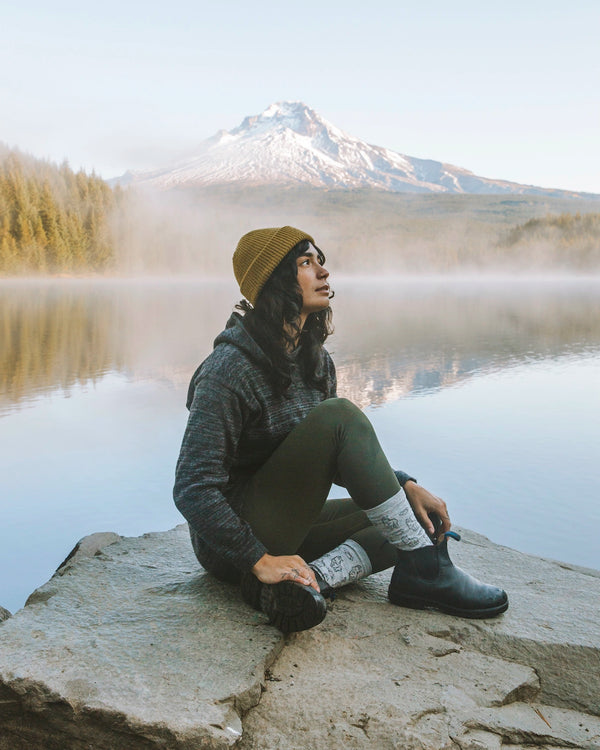 Woman in The Hoodie Charcoal / Dark Grey Alpaca Hoodie Sweater on Rock in Front of Mountain Lake – PAKA Apparel
