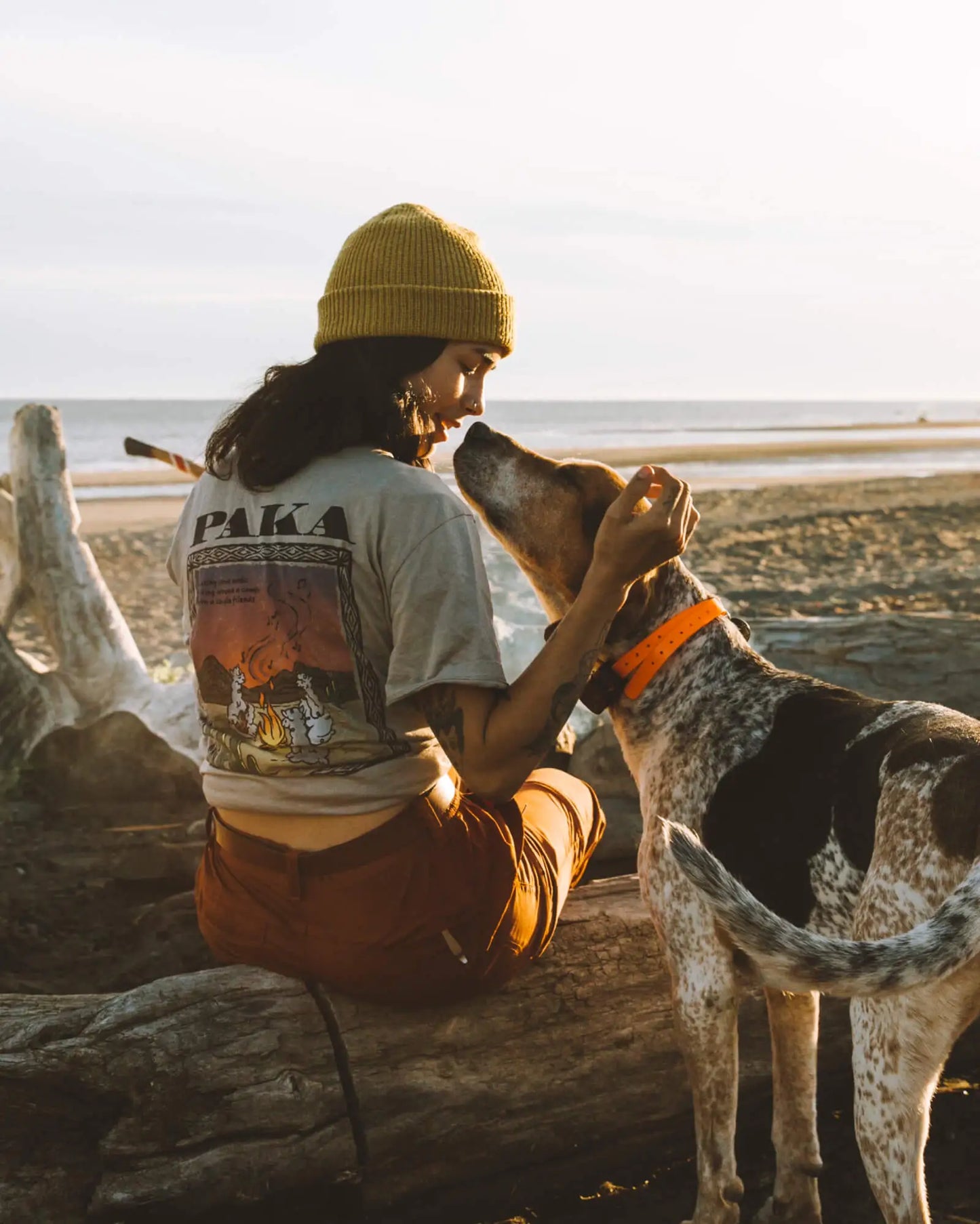 Model wearing Paka t-shirt with puppy around campfire