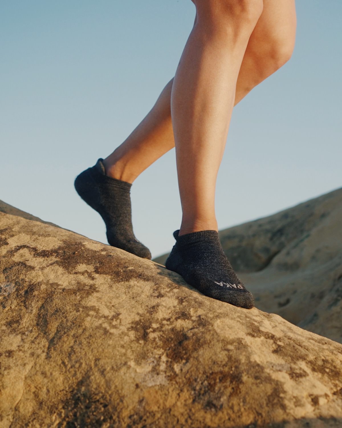 Woman walking down rock wearing dark grey alpaca ankle socks 