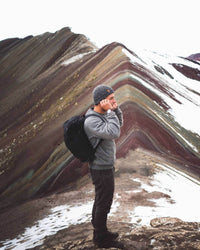 Male Hiker Wearing Charcoal Grey Marled Beanie Alpaca Wool Hat on Rainbow Mountain in Peru – PAKA Apparel