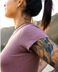 Side Shoulder-Height View of Tattooed Women in Natural Alpaca V Neck T-Shirt in Iris / Pink – PAKA Apparel