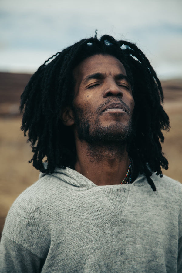 Meditative Man with Eyes Closed Wearing The Hoodie Light Grey Sustainable Knit Hoodie Sweater in Chinchero, Peru – PAKA Apparel