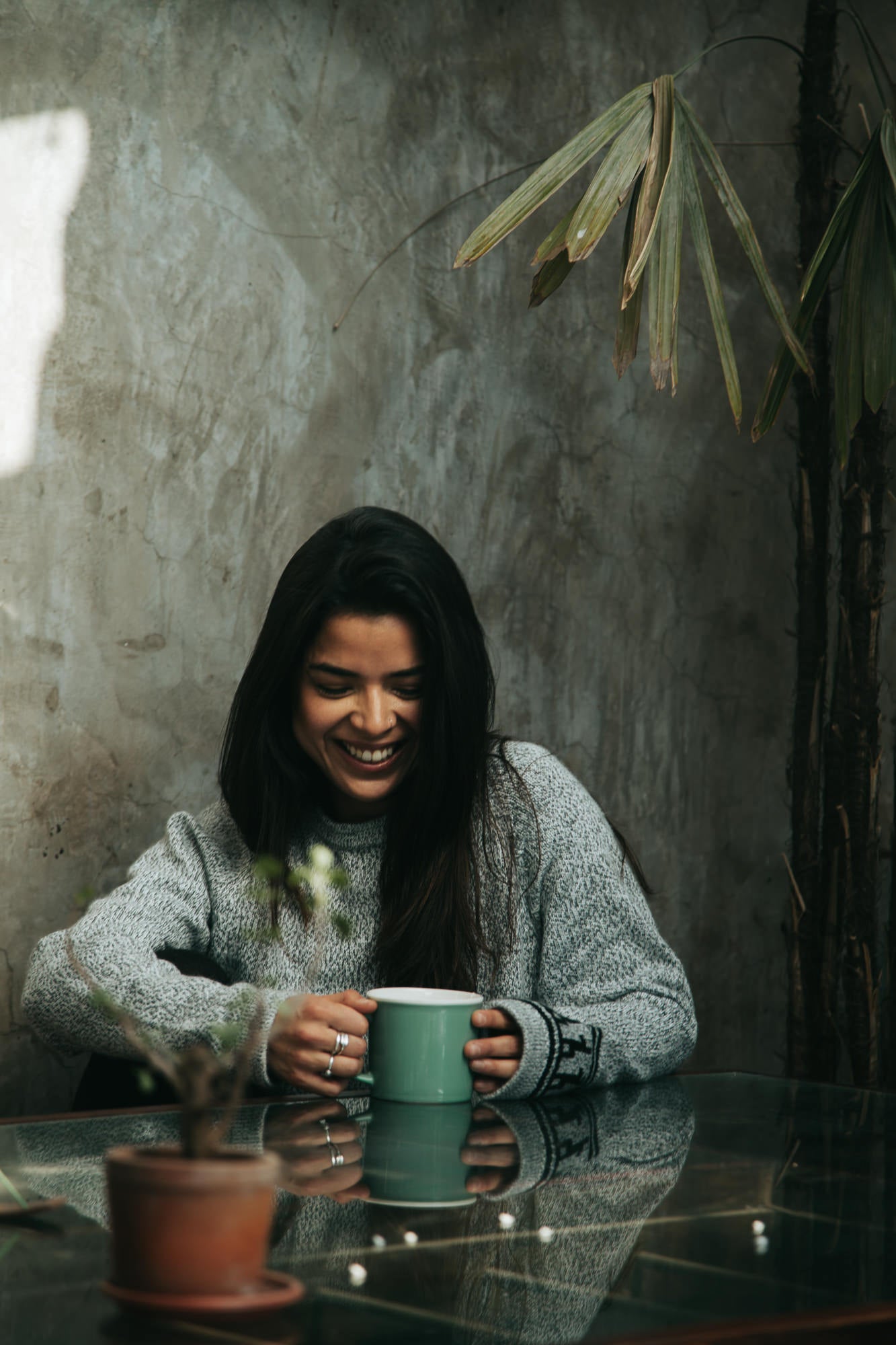 Model laughing and drinking coffee wearing the Costa alpaca sweater by Paka Apparel