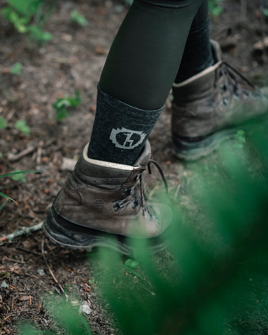 Model walking in dark grey Paka socks and boots on a trail