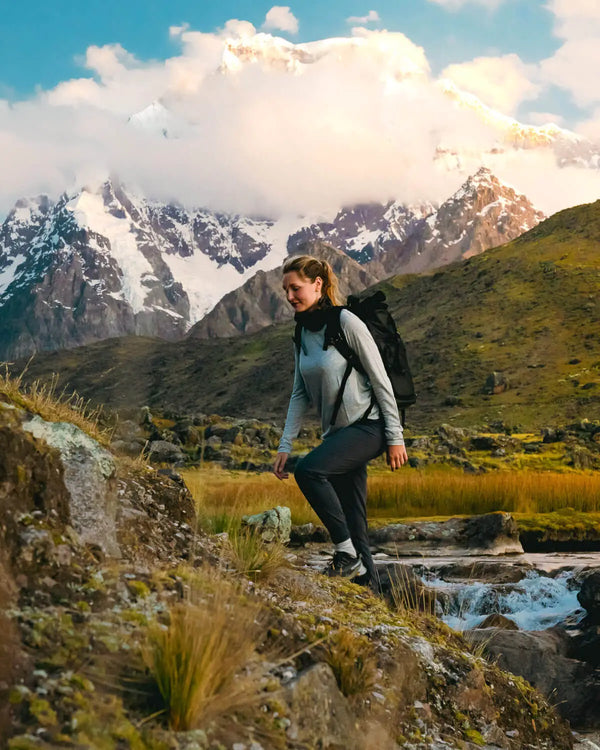 Woman Hiking in Heather Grey Aire Long Sleeve Shirt with Stream and Mountains in Background – PAKA Apparel